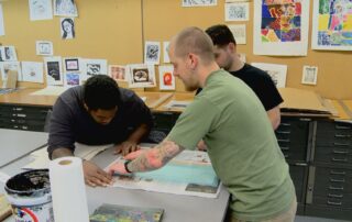 Three people work in an art studio to make homemade paper out of military uniforms at a Combat Paper workshop.