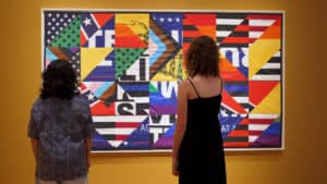 Two museum visitors stand in front of the artwork At the Twilight's Last Gleaming? (2021), by Hank Willis Thomas, at the Zimmerli Art Museum