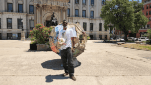 Nyugen Smith stands with the giant soccer ball he created for the 2026 World Cup, installed in front of City Hall in Jersey City.
